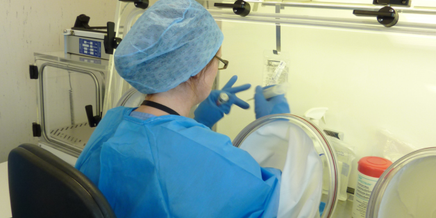 A woman in a lab coat operates a machine, focused on her work in a laboratory setting.