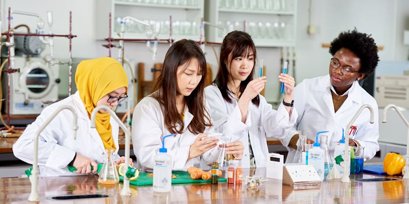Students in lab coats experimenting in laboratory at the School of Food Science and Nutrition, University of Leeds
