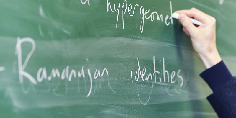 A hand writing on a chalkboard during a Centre for Doctoral Training lecture