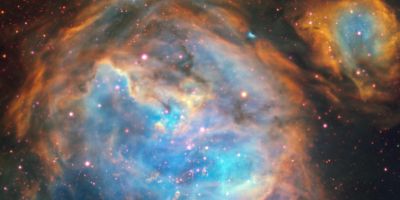 Colourful nebula with glowing blue and orange gas clouds and scattered stars in deep space.