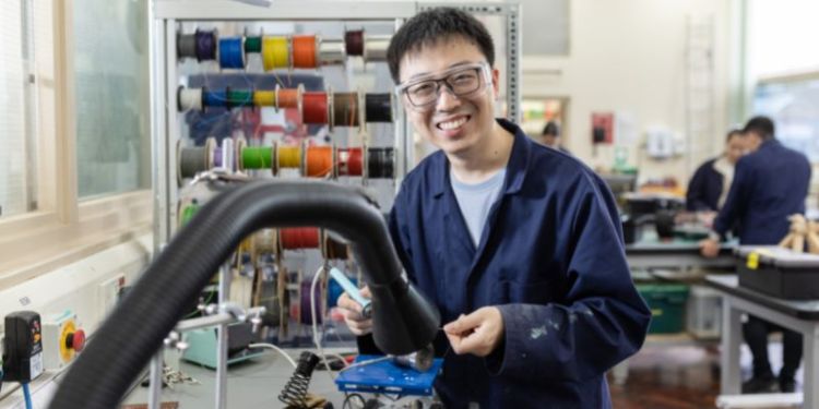 A portrait of Xiang Mao in a workshop in the School of Mechanical Engineering, soldering. 