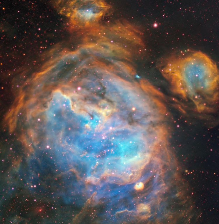 Colourful nebula with glowing blue and orange gas clouds and scattered stars in deep space.