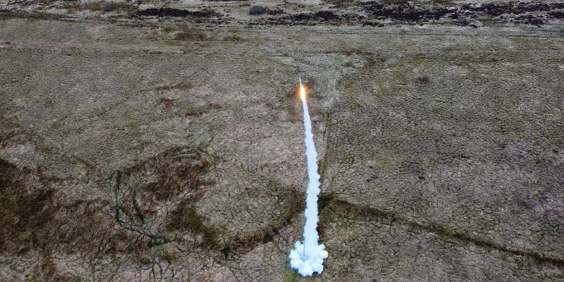 The Pathfinder rocket, taken from a drone, flying up in to the air, in the background is the Scottish mooreside.