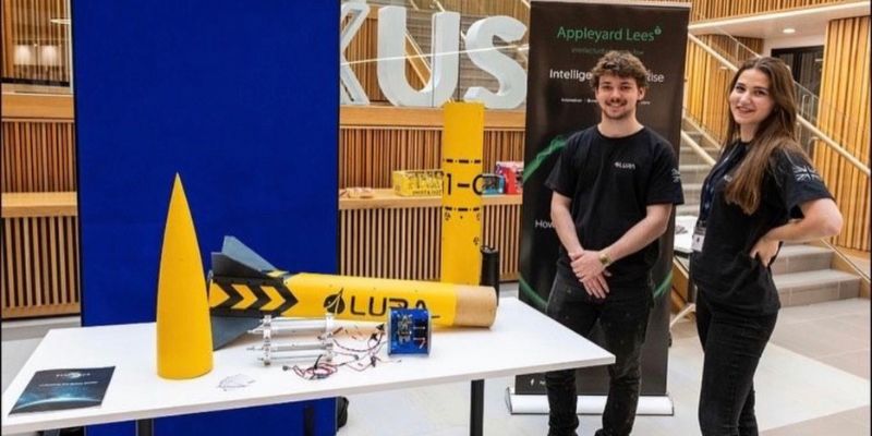 A photograph of Jake Hollyman and a fellow student stood next to a small rocket in the Nexus building at the University of Leeds.