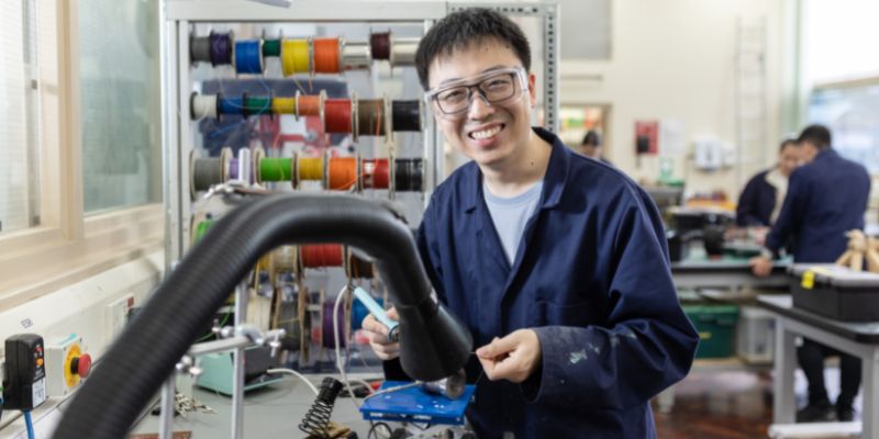 A portrait of Xiang Mao in a workshop in the School of Mechanical Engineering, soldering.