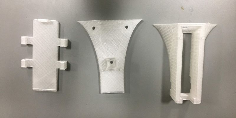 A photograph of three pieces of 3D printed medical engineered aides.