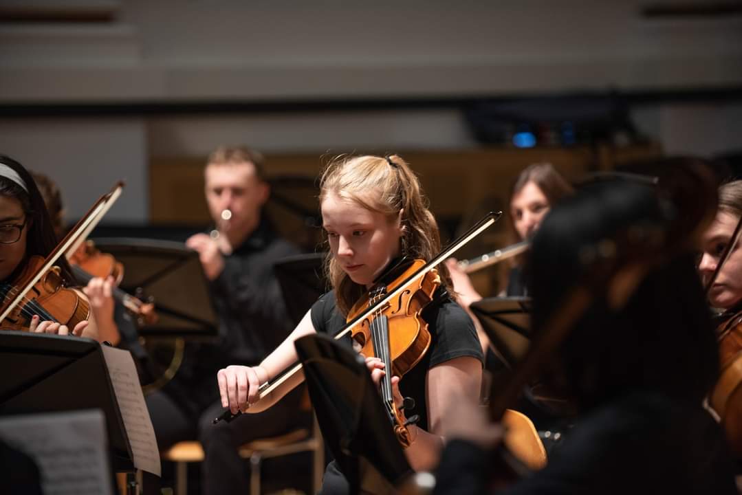 Female student playing the violin in an orchestra