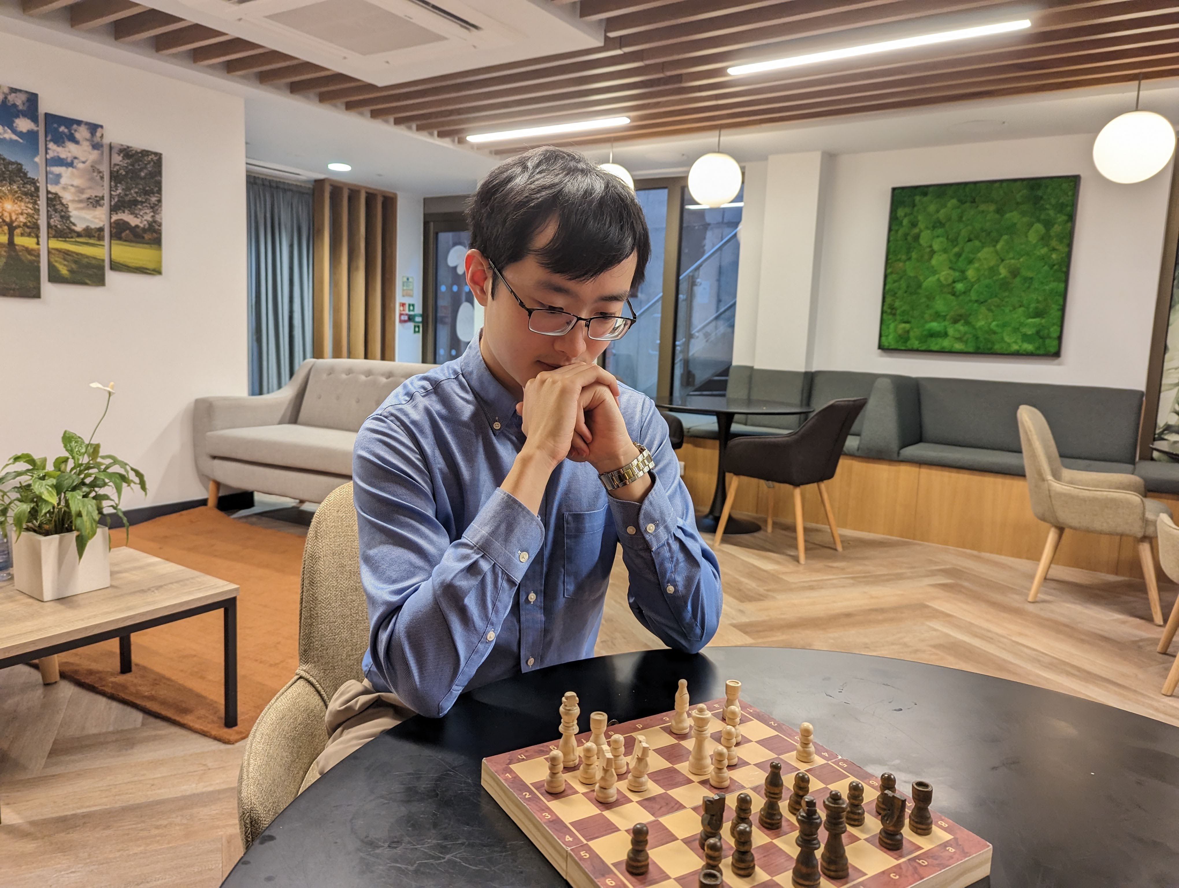 Muyou Li plays chess in a cafe