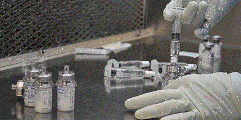 Image show hands of pharmacist in cleanroom wearing gloves and working with syringes and vials