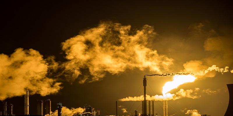 Smoke being emitted from factory chimneys at sunset