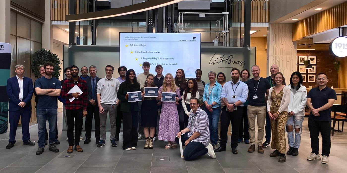 A group photo of the interns and staff who took part in the Summer Internship Scheme Celebrations 2023, stood in the foyer of the Sir William Henry Bragg Building at the University of Leeds.