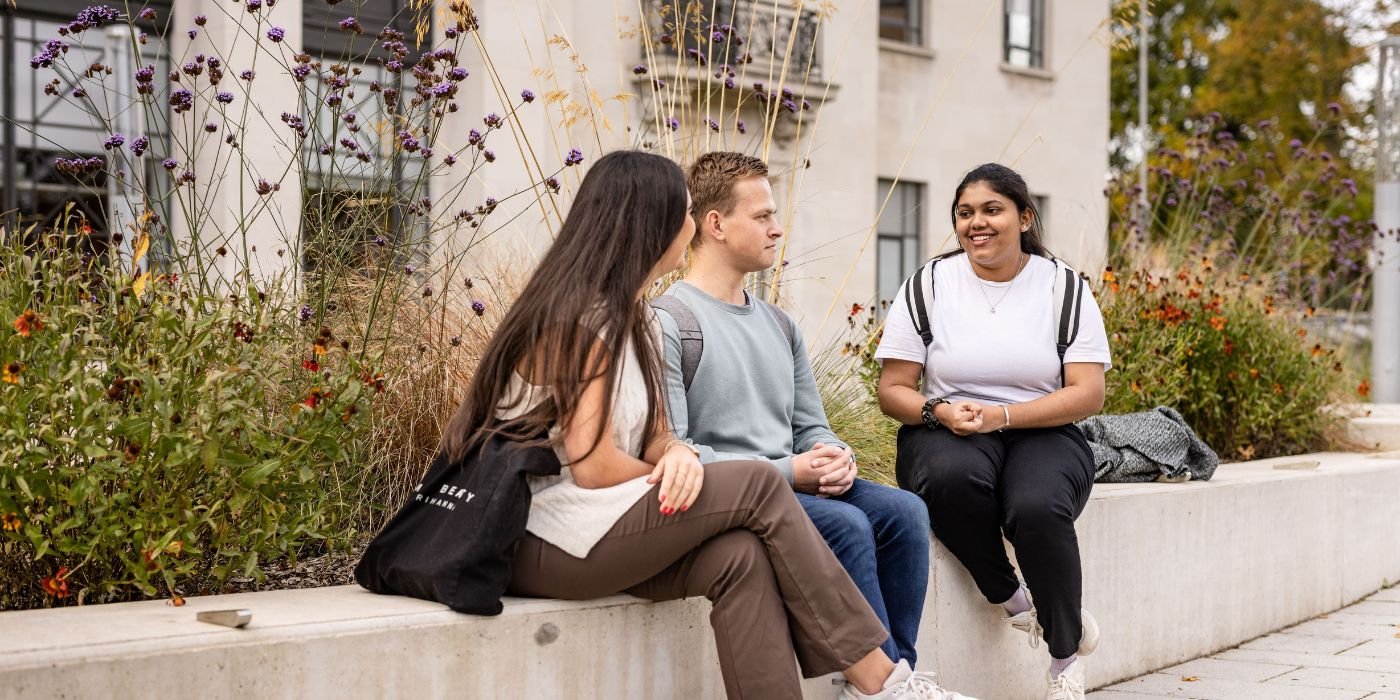Students sitting on a wall outside the Sir William Henry Bragg Building.
