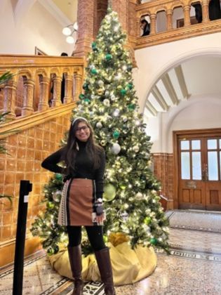 Harshita Garg standing by the Christmas tree in the great hall at the University of Leeds