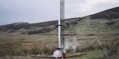 The Pathfinder rocket launching. The rocket is attached to it's guide rail and there is smoke and fire coming out at the bottom.