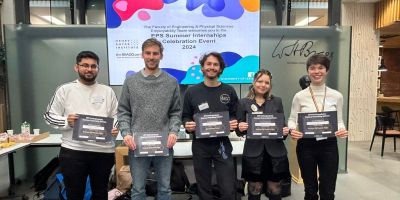 Four students holding their prize certificates in the Bragg building atrium.