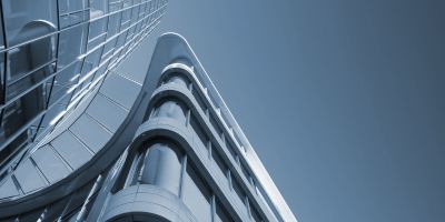 A photograph of the top of a skyscraper building, taken at an angle with the sky in the background.