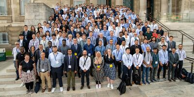 Dozens of attendees of the Leeds-Lyon Symposium 2023 on the Parkinson Building steps.