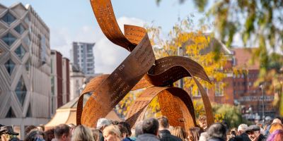 The Ribbons sculpture in Leeds on a sunny day, surrounded by people.