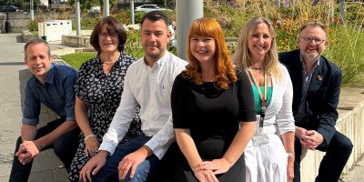 The six members of the TALENT team, sitting outside of the Bragg Building and smiling at the camera