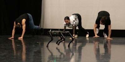A robot dog with dancers posing in the same position as the robot