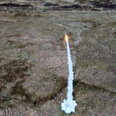 The Pathfinder rocket, taken from a drone, flying up in to the air, in the background is the Scottish mooreside.