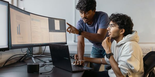 two male students looking at a graph on a computer screen
