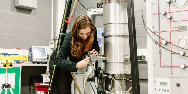 A woman working with a metal laboratory machine