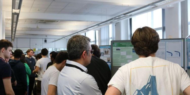 A photo of the School of Mechanical Engineering's Poster Showcase, with a group of attendees, made up of students and staff looking at the project work posters.