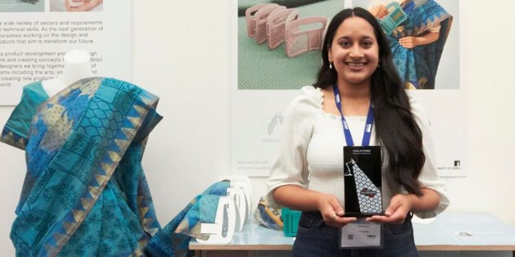 A student stood next to her booth at New Designers exhibition in London, showing her project work.