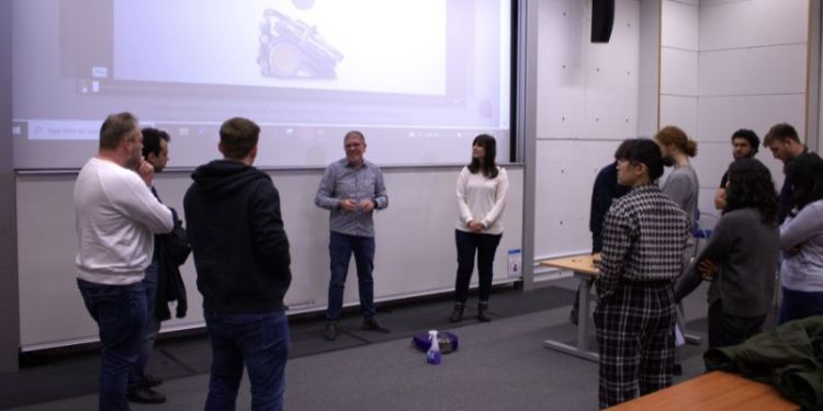A photograph of Prof. Robert Deaves demonstrating the 360VisNav in a lecture theatre, surrounded by a group of students.