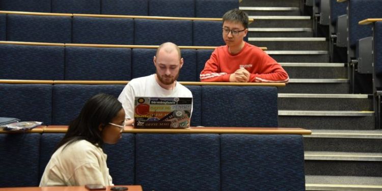 A photograph of Xiang Mao and two other students working together in a lecture theatre.