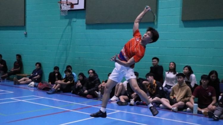 Kent playing badminton with a crowd watching