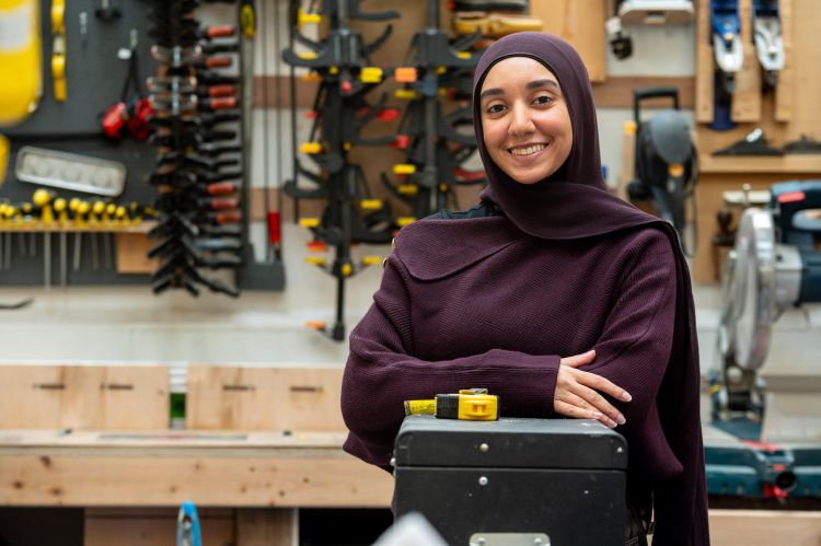 Fareda AlWakeel standing in a workshop surrounded by tools