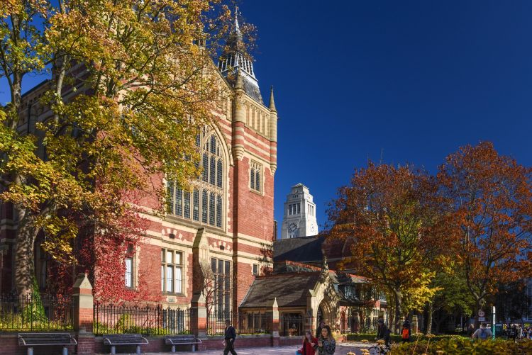 The University of Leeds Great Hall in autumn, with colourful trees and the Parkinson Building tower in the background.