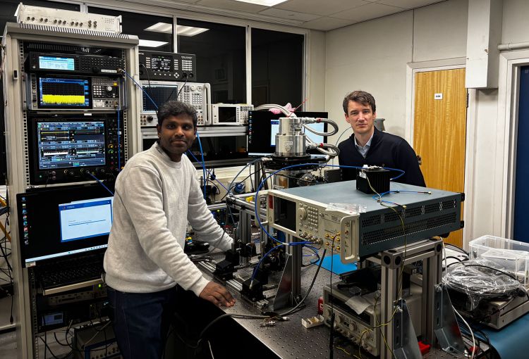 Dr Jayaprasath Elumalai and Dr Joshua Freeman standing around various pieces of technology and wiring making up their terahertz setup