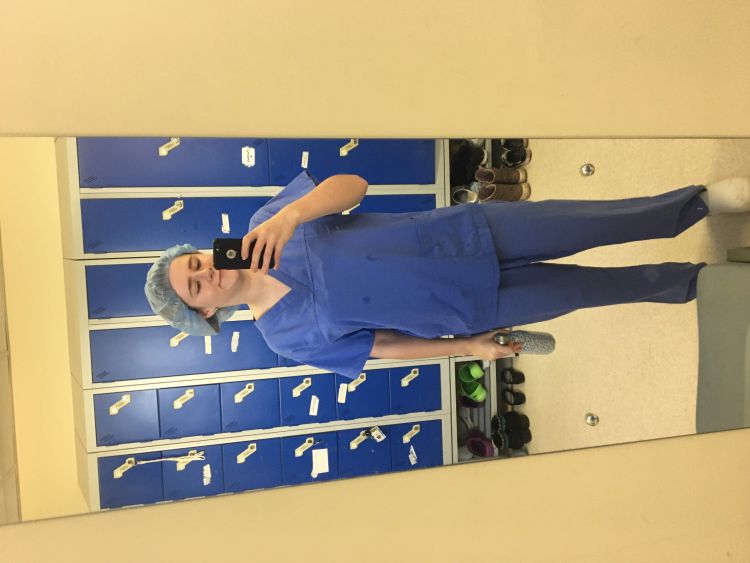 Martha Hayward in medical scrubs stood in front of a mirror.