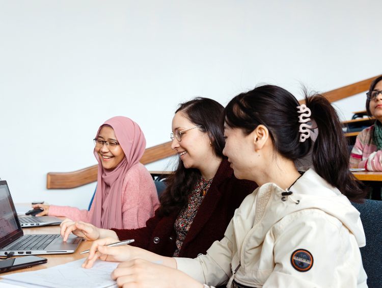 Image of three girls including PhD student Karen Quintanilla studying in a lecture theatre at the University of Leeds