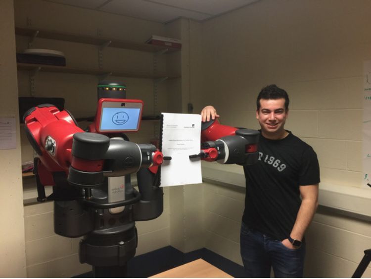 Picture of Rafael Papallas with the robot he used for his Final Year Project as an undergraduate in 2017. The robot holds his FYP report.