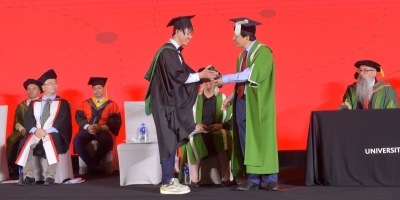 A student receives their degree from Professor Hai-Sui Yu.