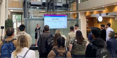 A photography of a crowd of people listening to a speech at the celebration event for the Faculty of Engineering and Physical Sciences Summer Internship Scheme.