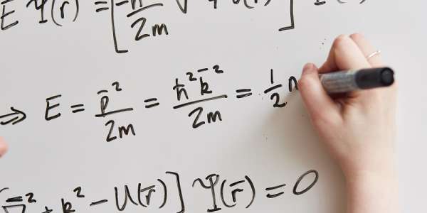 Equations written on a whiteboard, representing theoretical physics research