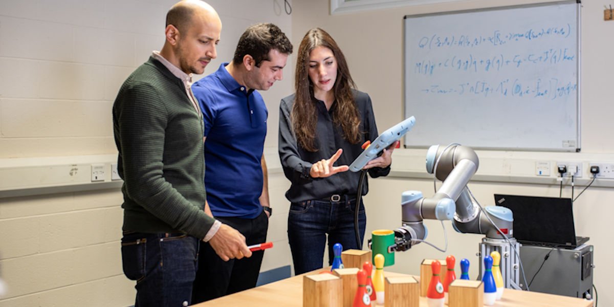 A group of 3 people working on robotics in a workshop