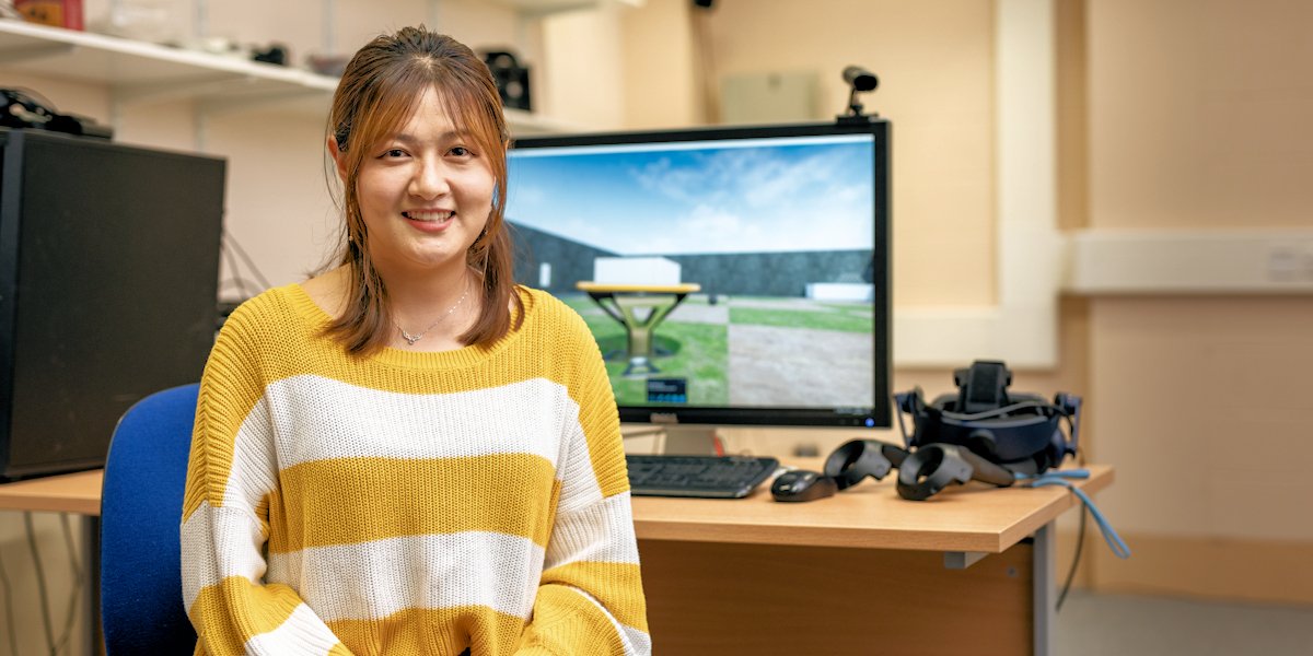 Postgraduate researcher portrait picture, with a computer in the background