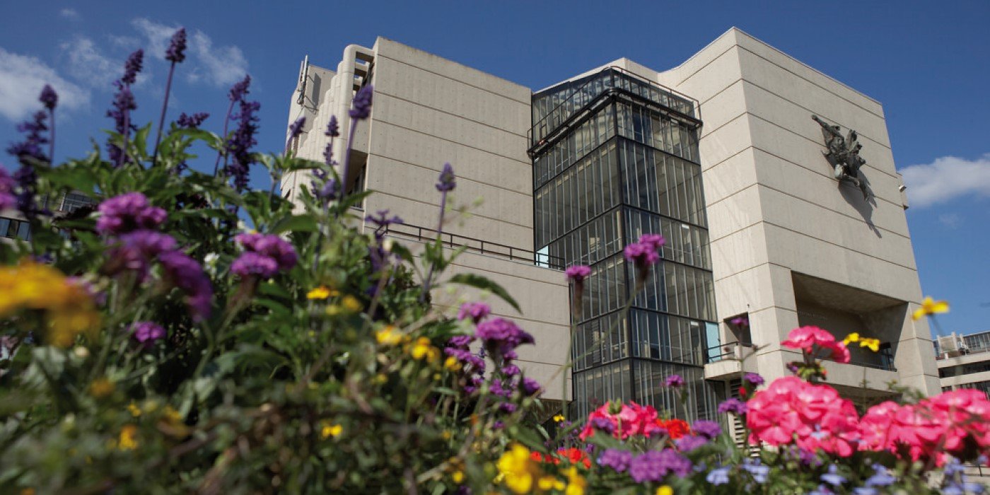 A ground level view of the Roger Stevens building surrounded by flowers
