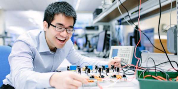 Male UG elec student with circuit board in basement lab b55