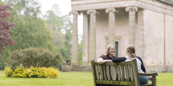 Two female students sit on a bench in St George's fields