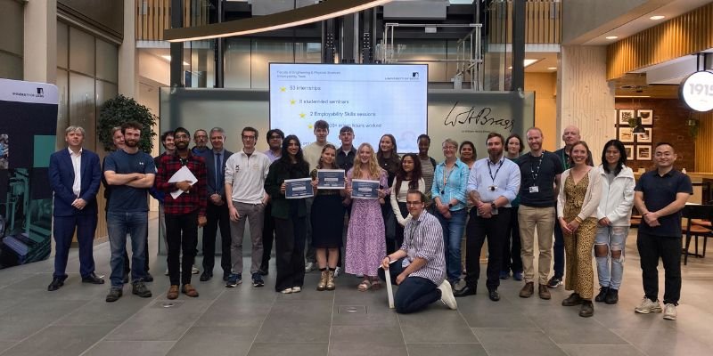 A group shot of the student interns from the Summer Internship Scheme Celebrations 2023, stood in the Sir William Henry Bragg Building foyer.